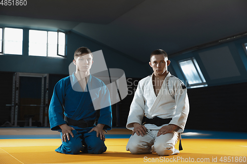 Image of Two young judo fighters in kimono posing comfident in the gym, strong and healthy