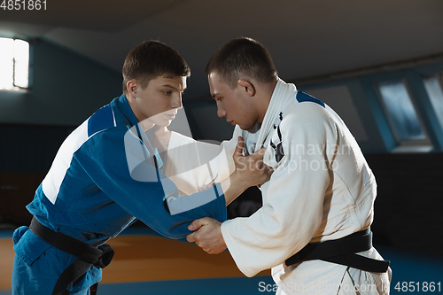 Image of Two young judo fighters in kimono training martial arts in the gym with expression, in action and motion