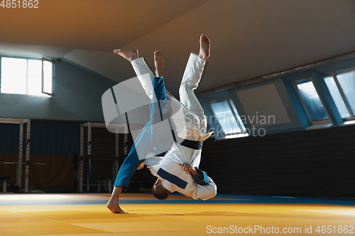 Image of Two young judo fighters in kimono training martial arts in the gym with expression, in action and motion