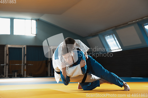 Image of Two young judo fighters in kimono training martial arts in the gym with expression, in action and motion