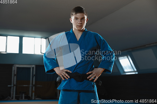 Image of Young judo fighter in kimono posing comfident in the gym, strong and healthy