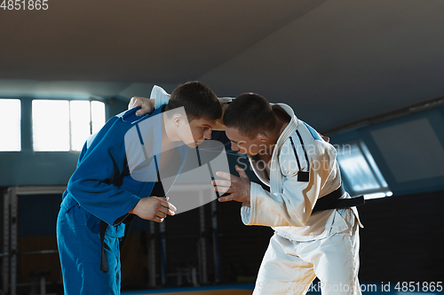 Image of Two young judo fighters in kimono training martial arts in the gym with expression, in action and motion