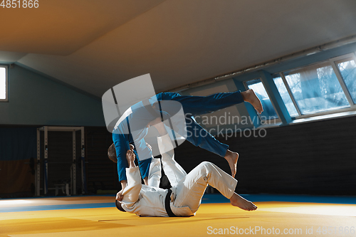 Image of Two young judo fighters in kimono training martial arts in the gym with expression, in action and motion