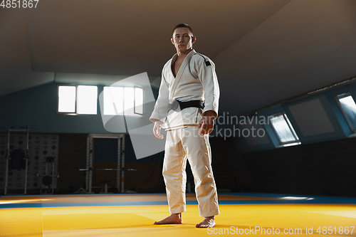 Image of Young judo fighter in kimono posing comfident in the gym, strong and healthy