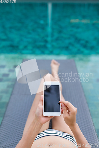 Image of Woman use of mobile phone with swimming pool