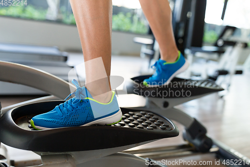 Image of Woman doing exercises in the gym on elliptical cross trainer