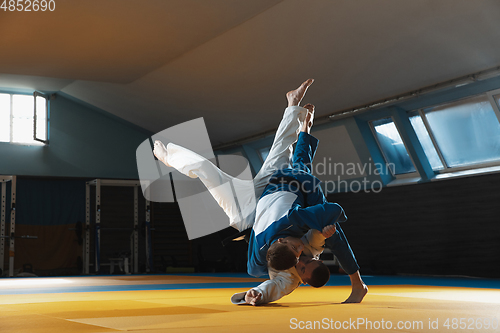 Image of Two young judo fighters in kimono training martial arts in the gym with expression, in action and motion