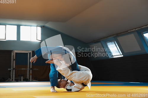 Image of Two young judo fighters in kimono training martial arts in the gym with expression, in action and motion