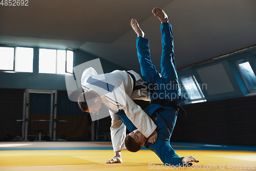 Image of Two young judo fighters in kimono training martial arts in the gym with expression, in action and motion