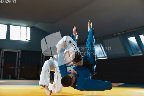 Image of Two young judo fighters in kimono training martial arts in the gym with expression, in action and motion