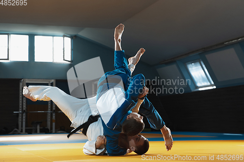 Image of Two young judo fighters in kimono training martial arts in the gym with expression, in action and motion