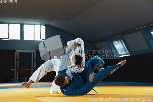 Image of Two young judo fighters in kimono training martial arts in the gym with expression, in action and motion