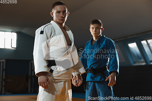 Image of Two young judo fighters in kimono posing comfident in the gym, strong and healthy