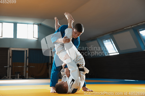 Image of Two young judo fighters in kimono training martial arts in the gym with expression, in action and motion