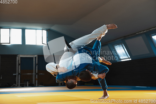 Image of Two young judo fighters in kimono training martial arts in the gym with expression, in action and motion