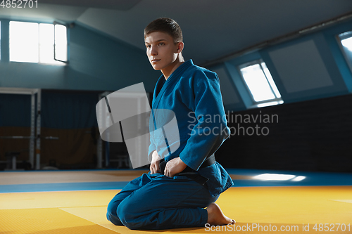Image of Young judo fighter in kimono posing comfident in the gym, strong and healthy