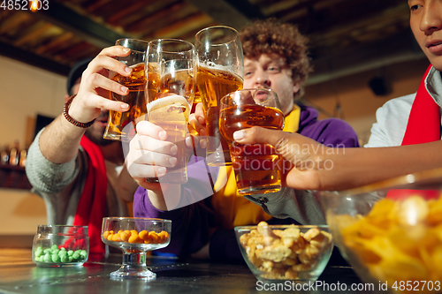 Image of Sport fans cheering at bar, pub and drinking beer while championship, competition is going