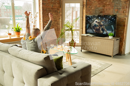 Image of Excited family watching martial arts, sport match at home, father and son