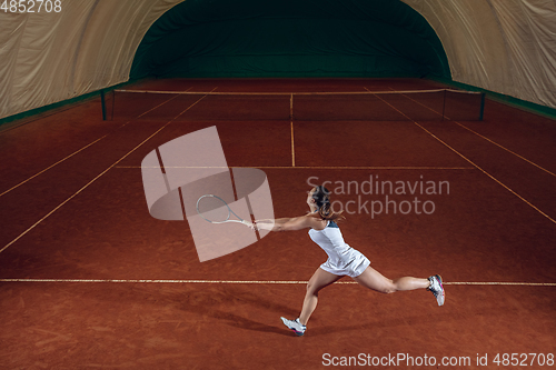 Image of Young caucasian professional sportswoman playing tennis on sport court background