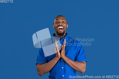 Image of Monochrome portrait of young african-american man on blue studio background