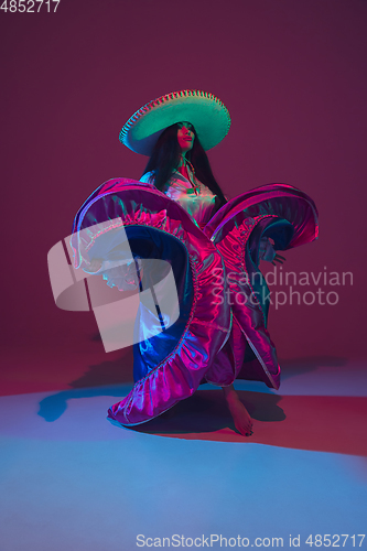 Image of Fabulous Cinco de Mayo female dancer on purple studio background in neon light