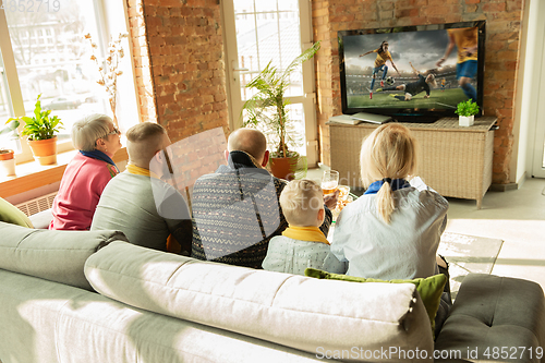 Image of Excited family watching female football, sport match at home