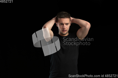 Image of Monochrome portrait of young caucasian man on black studio background