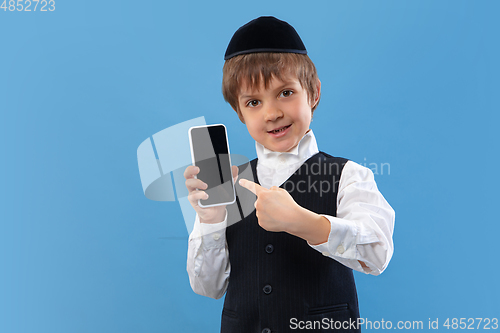 Image of Portrait of a young orthodox jewish boy isolated on blue studio background, meeting the Passover