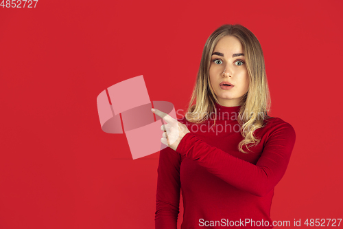 Image of Monochrome portrait of young caucasian blonde woman on red background