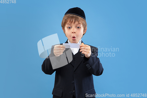 Image of Portrait of a young orthodox jewish boy isolated on blue studio background, meeting the Passover