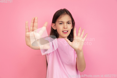 Image of Caucasian little girl portrait isolated on pink studio background, emotions concept