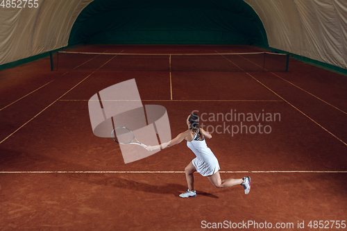 Image of Young caucasian professional sportswoman playing tennis on sport court background