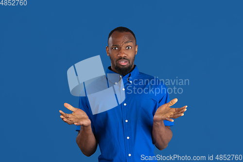 Image of Monochrome portrait of young african-american man on blue studio background