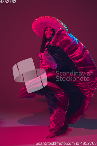 Image of Fabulous Cinco de Mayo female dancer on purple studio background in neon light
