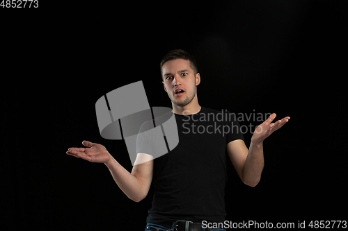 Image of Monochrome portrait of young caucasian man on black studio background