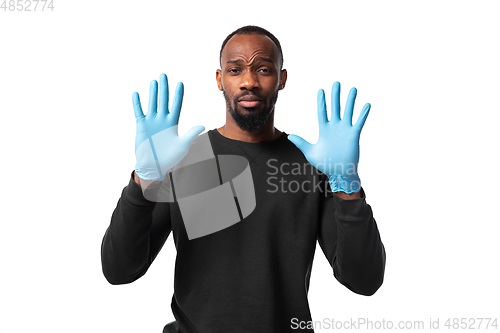 Image of How coronavirus changed our lives. Young man holding thermometer, taking temperature on white background