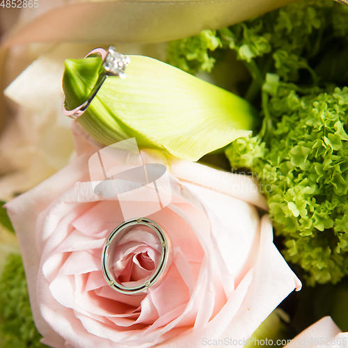 Image of wedding rings lie on a beautiful bouquet as bridal accessories