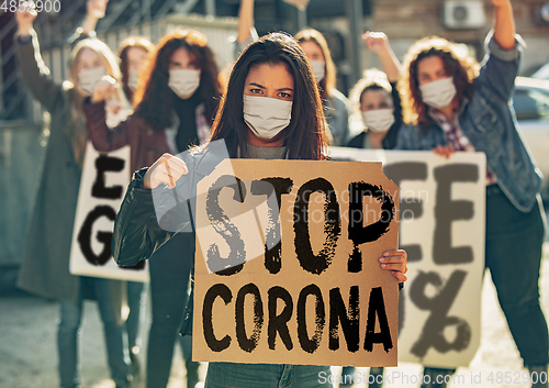 Image of Young people in face masks protesting of stop coronavirus pandemic on the street