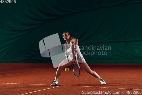 Image of Young caucasian professional sportswoman playing tennis on sport court background