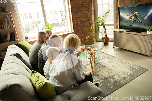 Image of Excited family watching rugby, sport match at home