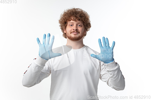 Image of How coronavirus changed our lives. Young man holding thermometer, taking temperature on white background