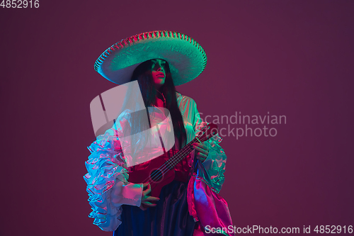 Image of Fabulous Cinco de Mayo female dancer on purple studio background in neon light