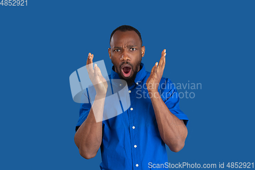Image of Monochrome portrait of young african-american man on blue studio background