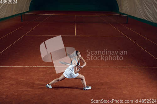 Image of Young caucasian professional sportswoman playing tennis on sport court background