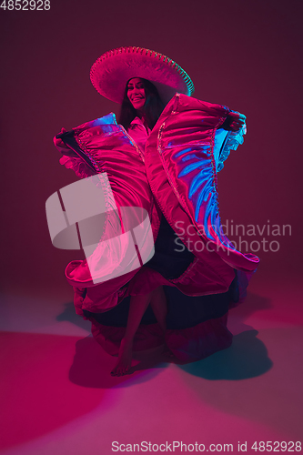 Image of Fabulous Cinco de Mayo female dancer on purple studio background in neon light