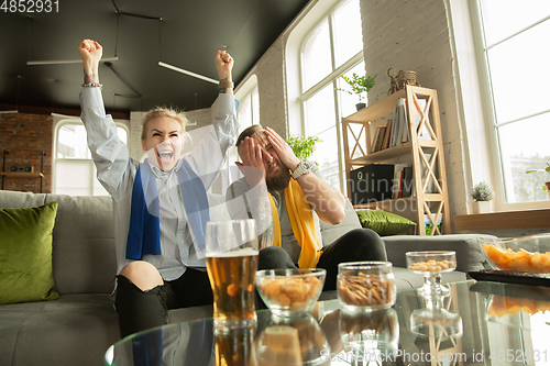 Image of Excited family watching football, sport match at home, beautiful couple