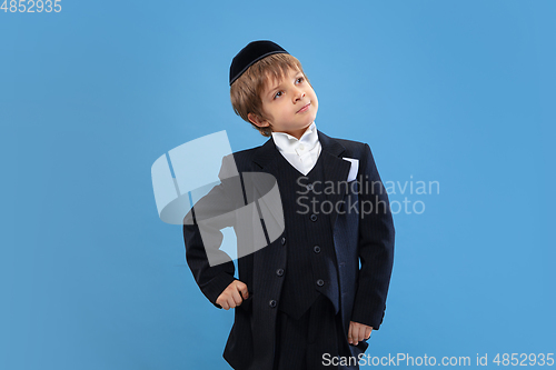 Image of Portrait of a young orthodox jewish boy isolated on blue studio background, meeting the Passover