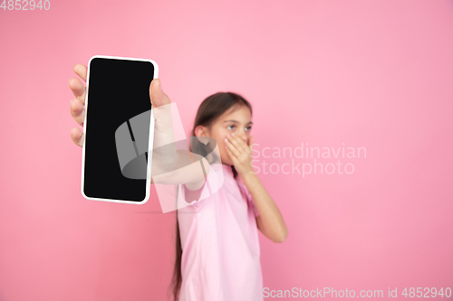 Image of Caucasian little girl portrait isolated on pink studio background, emotions concept