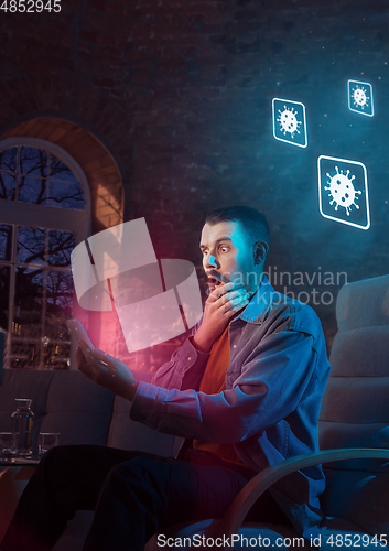 Image of Shocked, upset and sad man using gadgets to get information of coronavirus pandemic spread