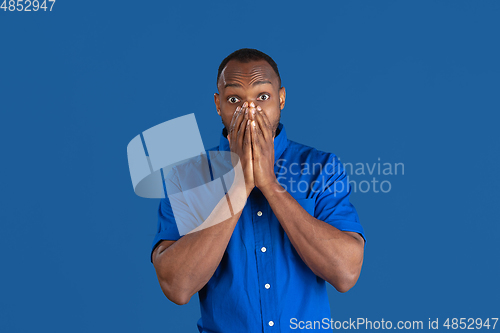 Image of Monochrome portrait of young african-american man on blue studio background